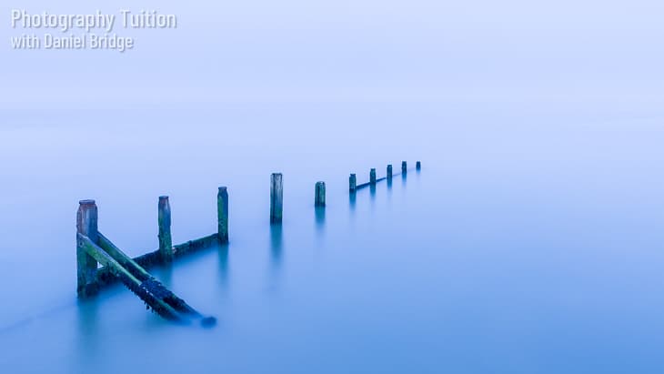 A long-exposure shot of a breakwater with cool blue tones